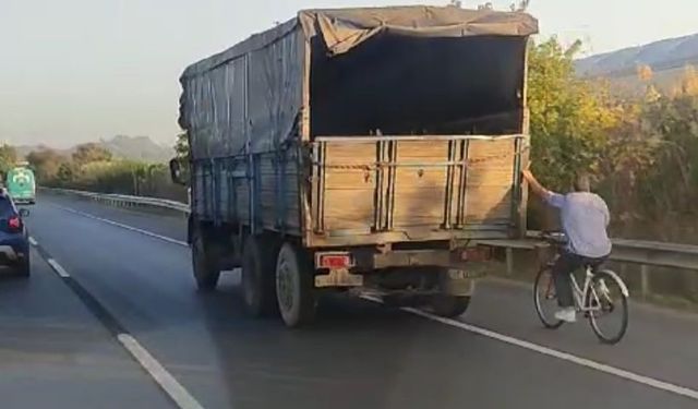 Hızla giden kamyonun arkasına tutunan bisikletli yürekleri ağza getirdi